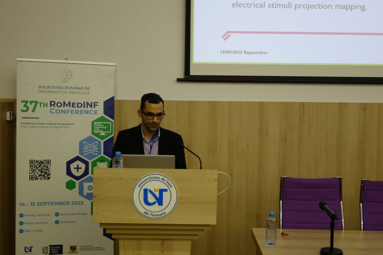 Man talking in front of a mic while presenting his paper.